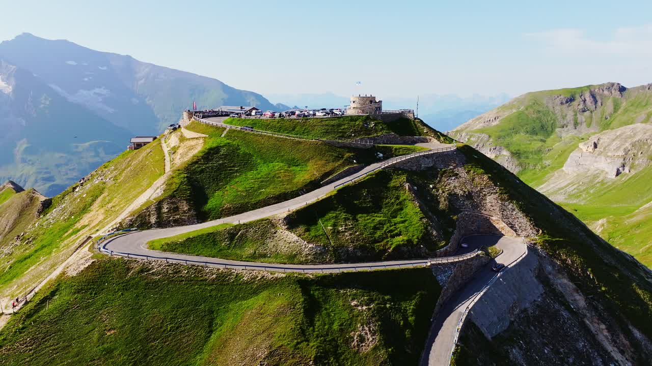Winding alpine road curves toward Edelweißspitze peak in golden sunset light
