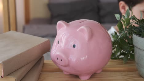 boy inserting coin into piggy bank