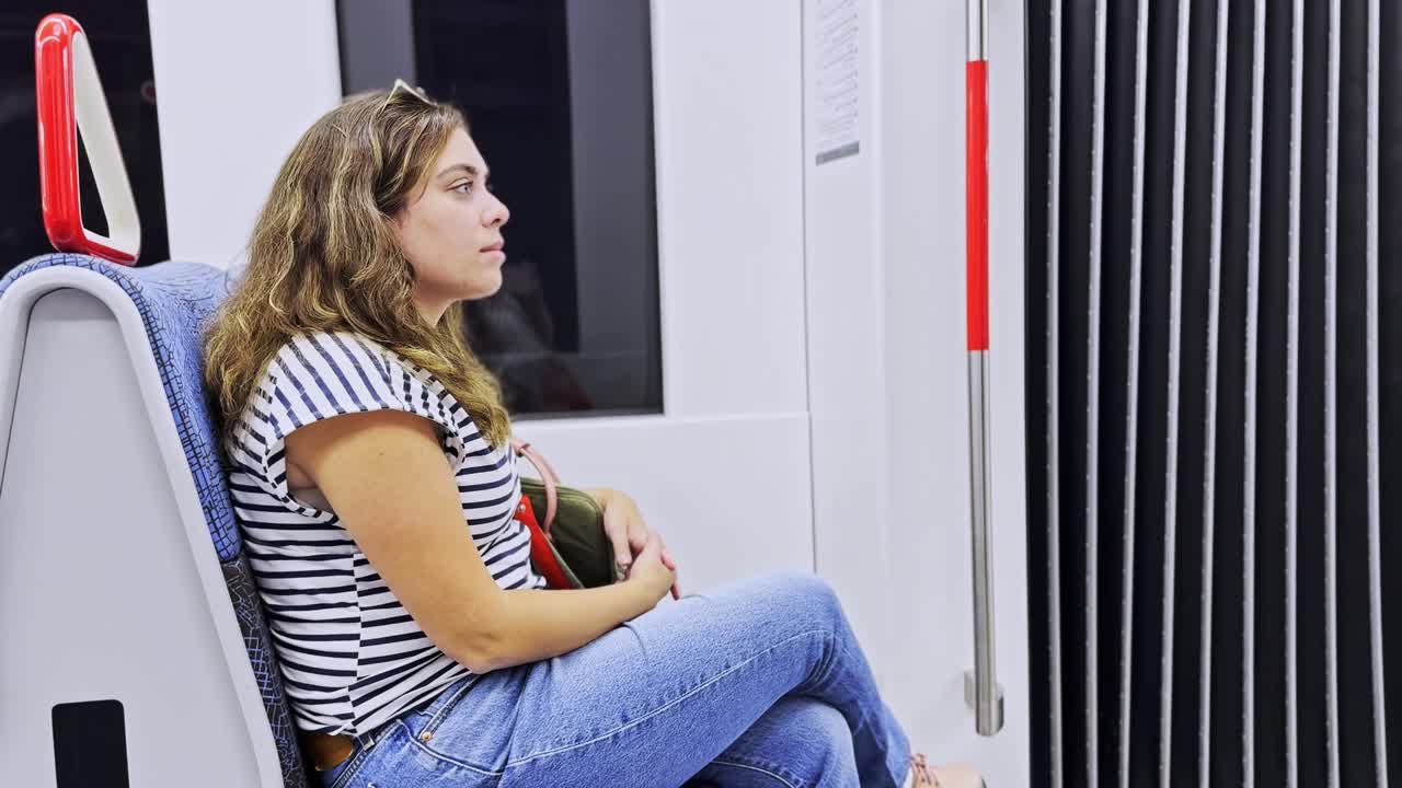 Donna pensierosa seduta in un treno della metropolitana che guarda altrove