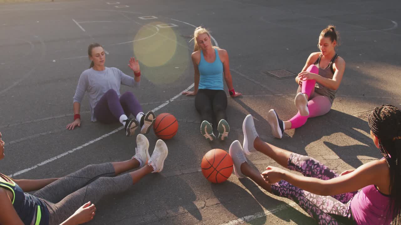 Diverse female basketball team wearing sportswear, stretching