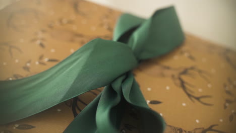 close up push in on christmas gift adorned with deer illustrations and a big green bow