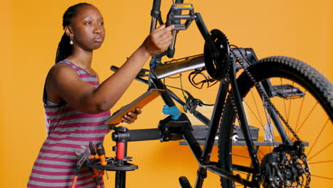 Engineer-with-tablet-in-hand-analyzing-damaged-bike-over-studio-background