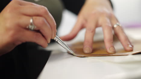 close-up of hands applying glue to leather with a brush