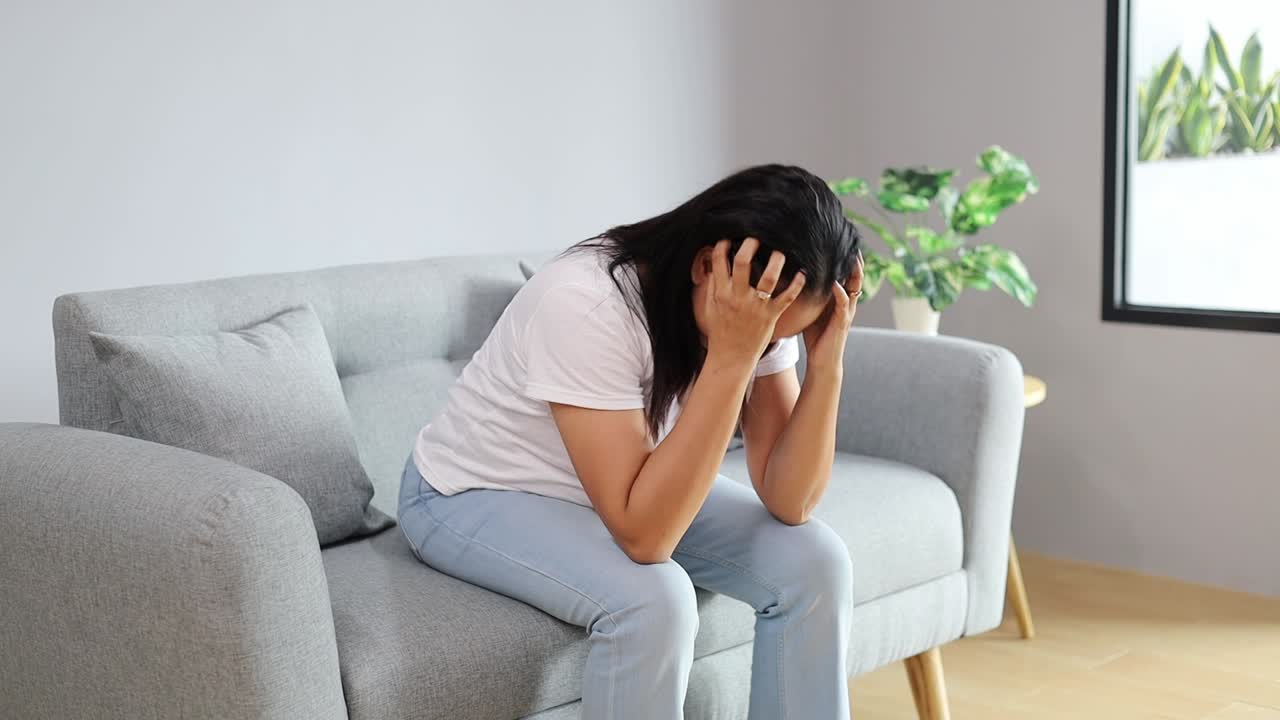 Asian housewife suffering from depression sitting on floor at home