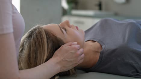 una fisioterapeuta masajeando a su paciente alrededor de la cabeza y el cuello.