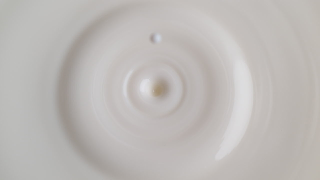 액체 표면에 떨어지는 우유 방울은 매크로와 느린 동작으로 스플래시 크로너와 파동을 만니다.