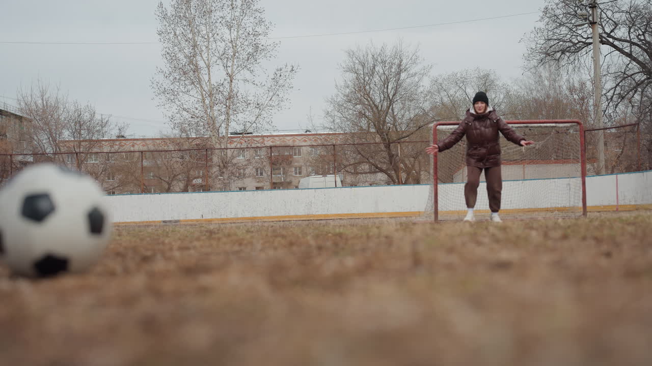 공격수가 골키퍼를 빠르게 제치고 지나가는 모습, 치열한 축구 연습 세션 중 진흙투성이 경기장 클로즈업, 활기찬 발놀림으로 진흙 운동장에서 골키퍼를 피하는 축구 선수를 보여주는 역동적인 장면