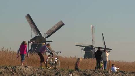 dutch citizens walk on a footpath in front of windmills