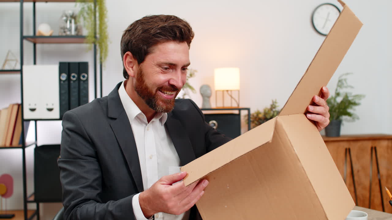 Middleaged businessman opens courier box carefully smiles at successful purchase and happy unboxing