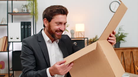 middleaged businessman opens courier box carefully smiles at successful purchase and happy unboxing