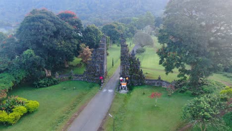 Antique-stone-gates-and-asphalt-road,-aerial-orbit-view