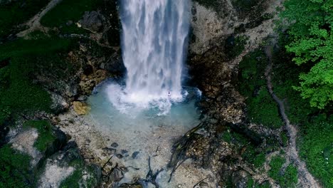 man with beard is doing waterfall-meditation under big waterfall