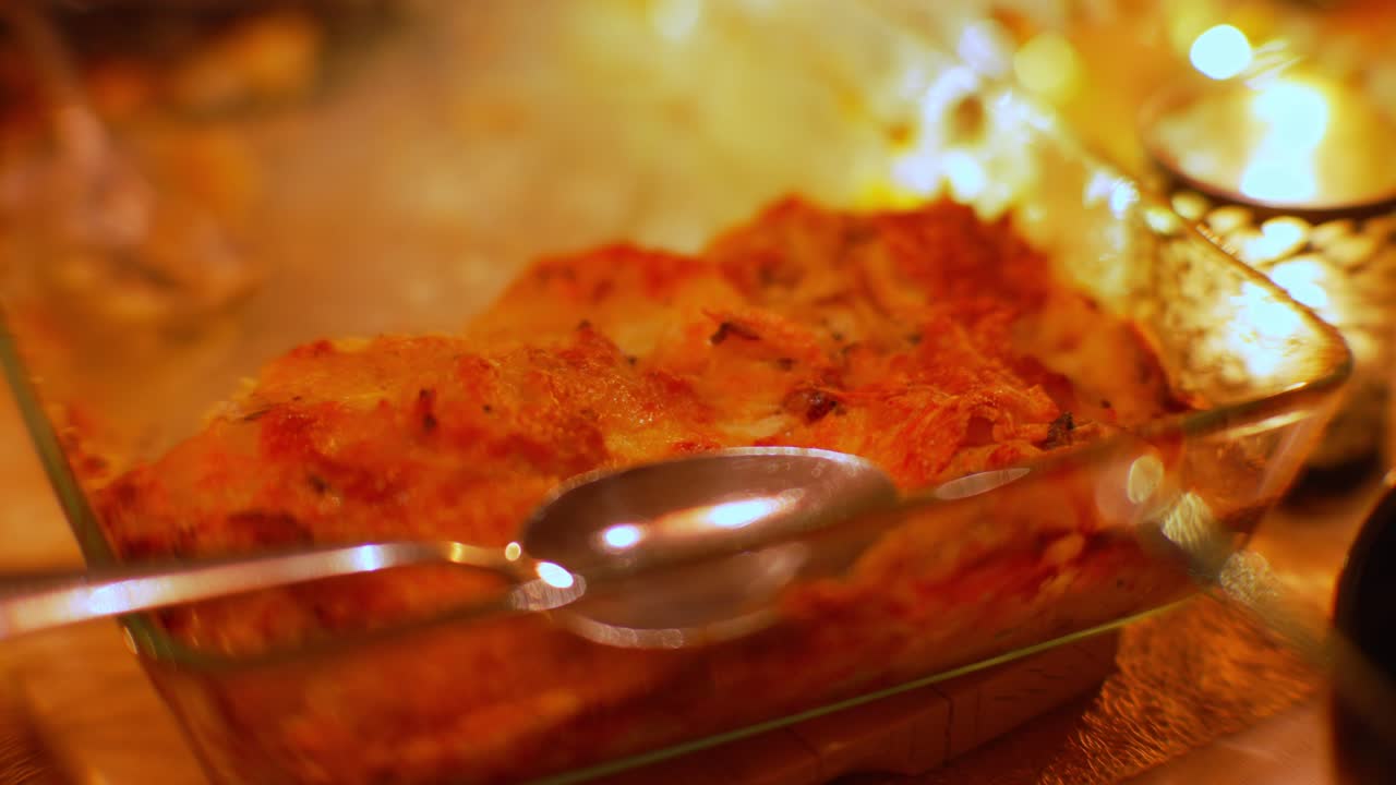 patato gratin con capa de queso crujiente en un plato en una mesa con velas