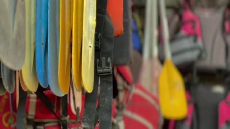 paletas de barco y chalecos salvavidas colgando de un estante