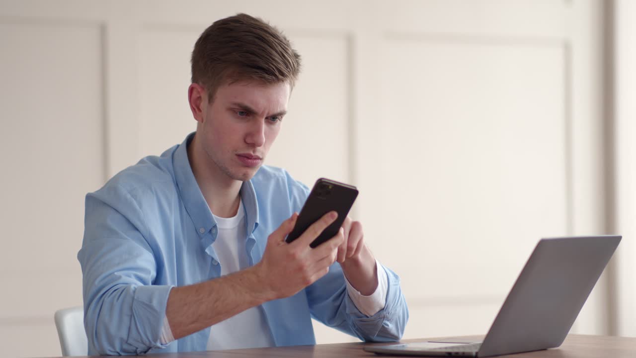 Young Man Working on Laptop and Using Phone
