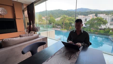 asian millennial entrepreneur working remotely in a luxurious home with pool view