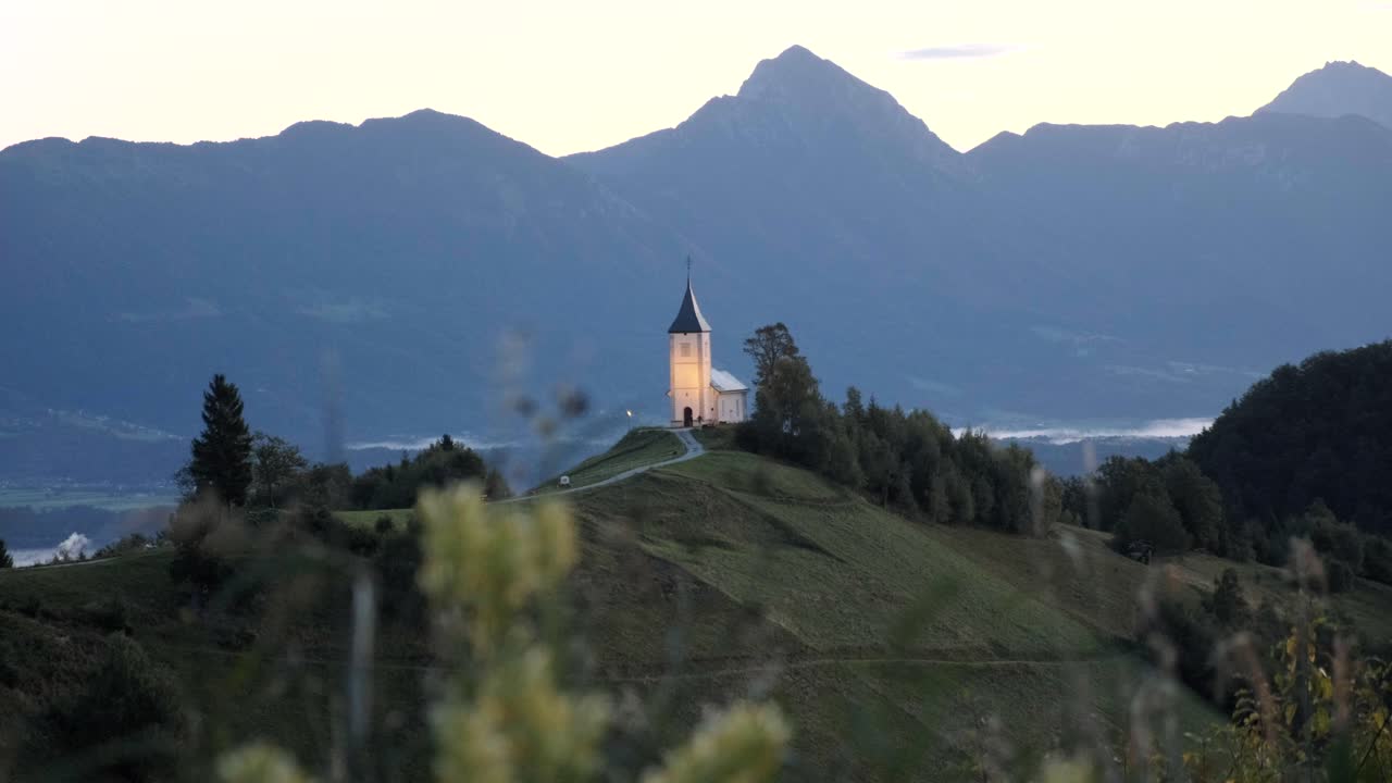 Jamnik church with the first rays of light on the iconic church on the hill in Slovenia with the mountains in the background