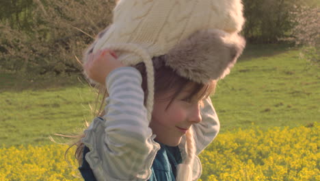 little girl putting a winter hat on her head while pretending to be a pilot