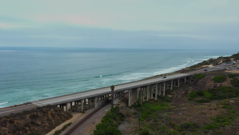 Fahrzeuge,-Die-Auf-Brücke-über-Bahngleise-Mit-Seelandschaft-In-Del-Mar,-San-Diego,-Kalifornien,-Usa-Fahren