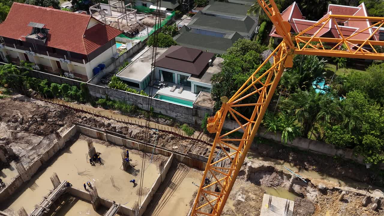 Aerial view of a construction site with a large crane and workers laying building foundations