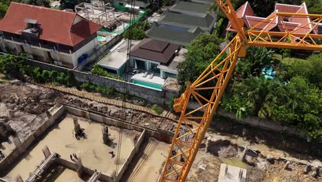 aerial view of a construction site with a large crane and workers laying building foundations