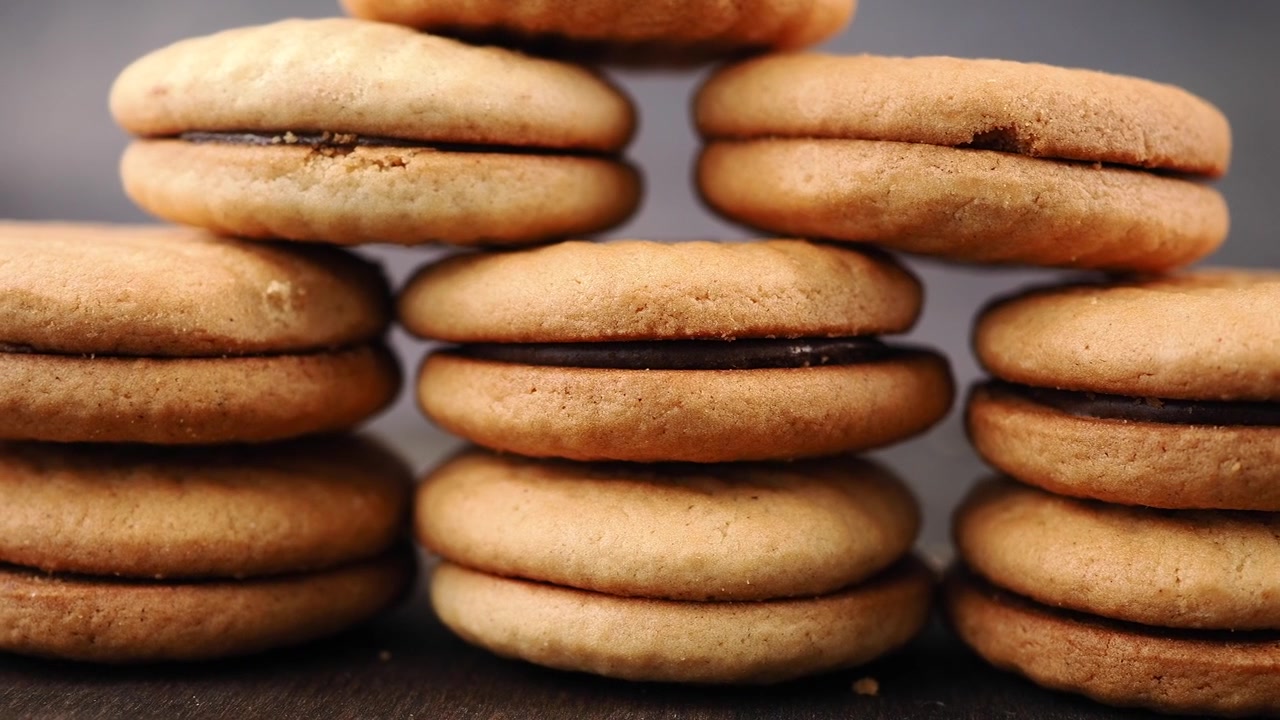 Primo piano di biscotti a sandwich dorati impilati con ripieno al cioccolato