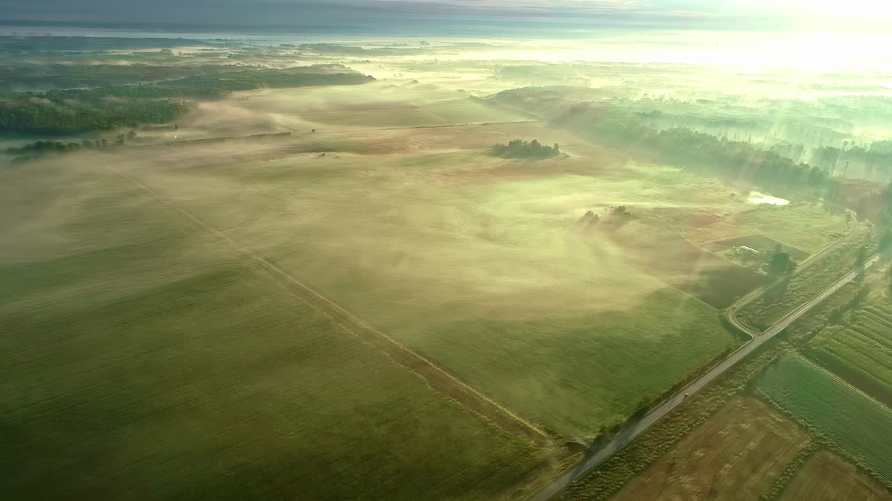 아침 시간 동안 흰 구름이 지나가는 녹색 농지 위로 공중 무인 항공기가 앞으로 이동합니다.