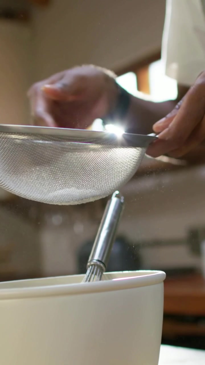 Vertical video: Starting recipe green apron cook holding sieve over kitchen bowl milk bottle front