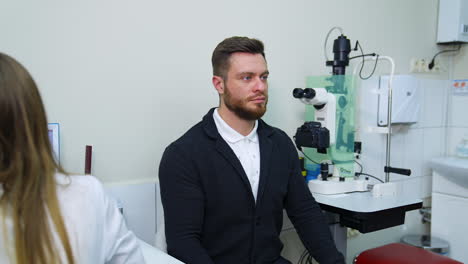 patient during vision test. young male patient checking up vision, closing his eye
