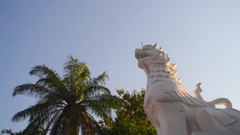 tiro giratorio en cámara lenta sobre la estatua del león del templo mirando hacia el cielo azul