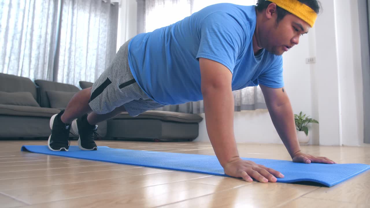 hombre con sobrepeso haciendo flexiones en casa