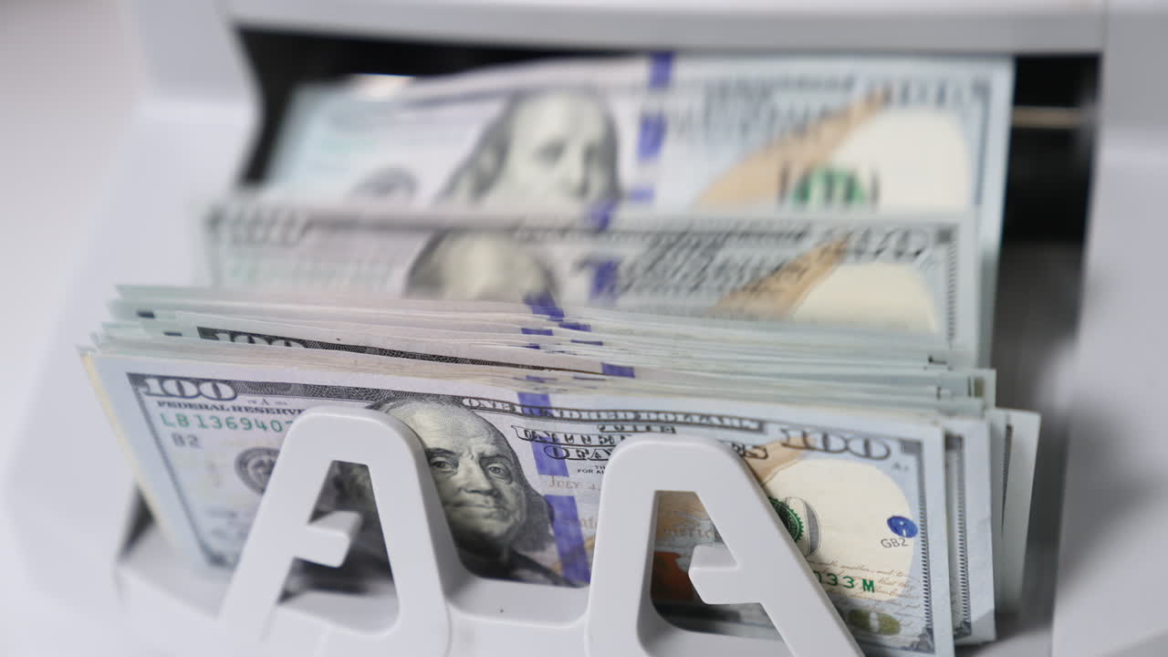 One hundred dollar wad being calculated in money counting machine. Benjamin Franklin portrait on the notes close up.
