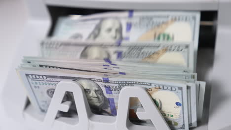 one hundred dollar wad being calculated in money counting machine. benjamin franklin portrait on the notes close up.