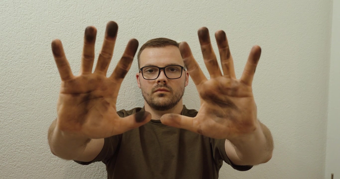 Man holding dirty hands toward the camera, highlighting contamination, poor hygiene, and need for cleaning and sanitation.