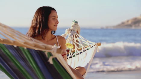 Cute-woman-holding-a-cocktail-in-a-hammock