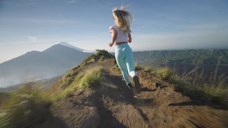 fearless blond woman running fast on mountain ridge of batur, high on life