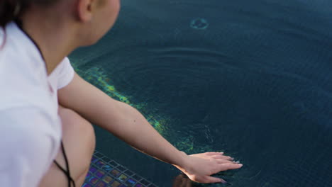 mujer tocando el agua en la piscina