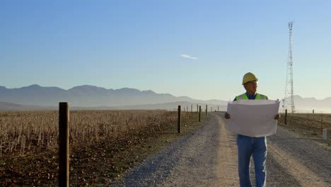 ingeniero masculino caminando con un plano en el parque eólico 4k