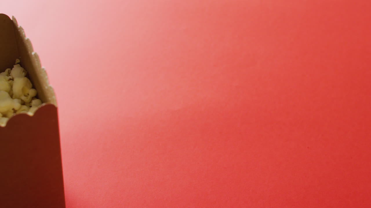video de un primer plano de una caja de palomitas de maíz sobre un fondo rojo
