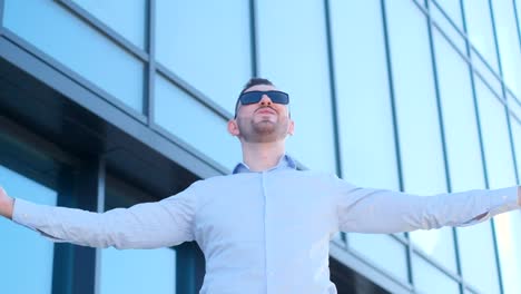 young office worker in sunglasses spreads arms wide looks around and rejoices business worker young office worker in sunglasses spreads arms wide looks around and rejoices business worker