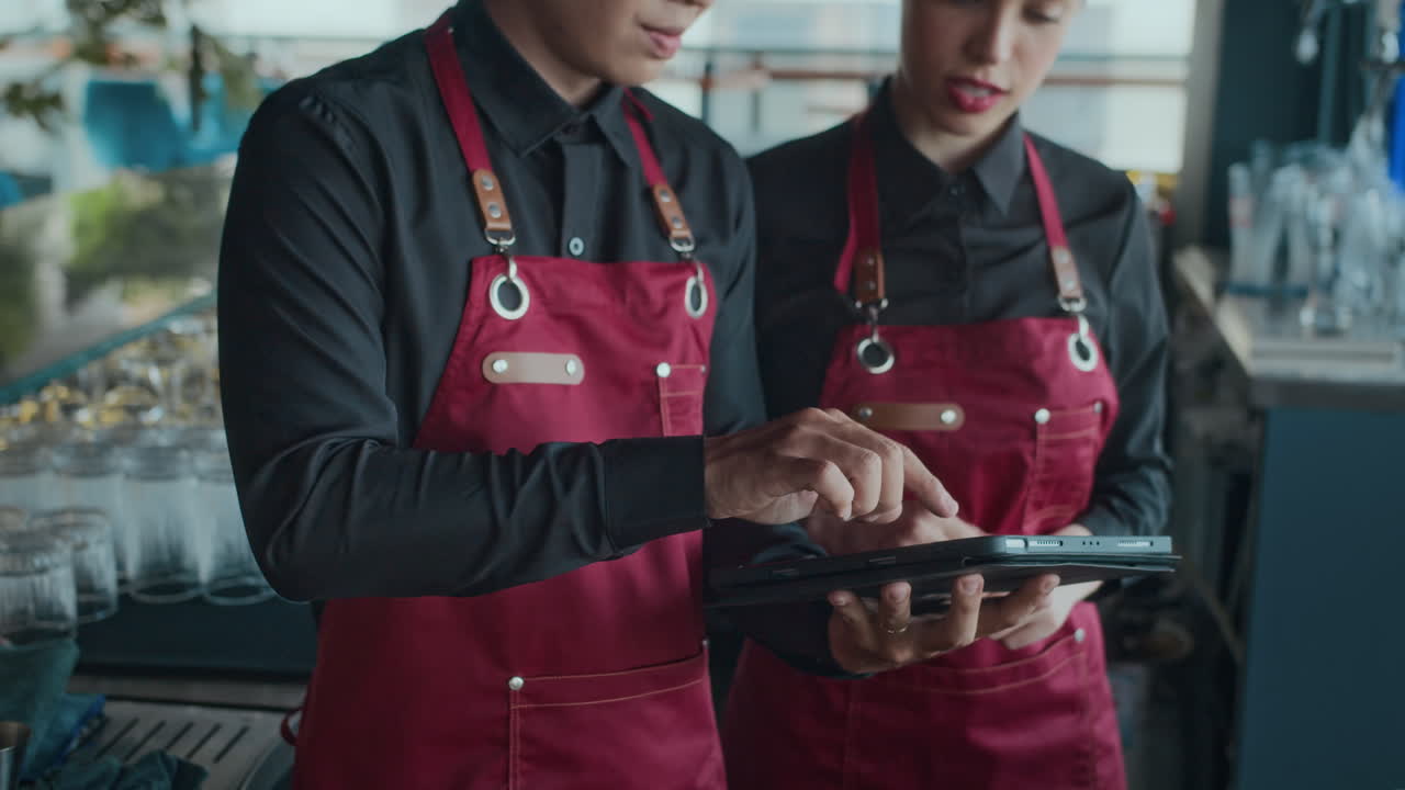 Bartender Tutoring Female Newcomer Using Tablet PC in Cafe