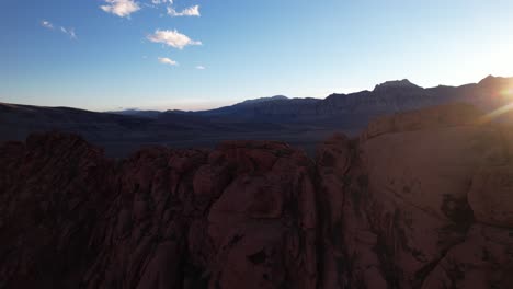 drone vuela cerca de la formación de roca roja que revela la pintoresca puesta de sol detrás del cañón de roca gigante en california, las vegas, ee.uu.