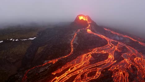 Imágenes-Cinematográficas-Aéreas-Capturadas-Por-Un-Dron-De-4k-Muestran-Un-Volcán-En-Erupción-De-Lava,-Con-Corrientes-Fundidas-Cayendo-En-Cascada-Desde-Su-Pico.