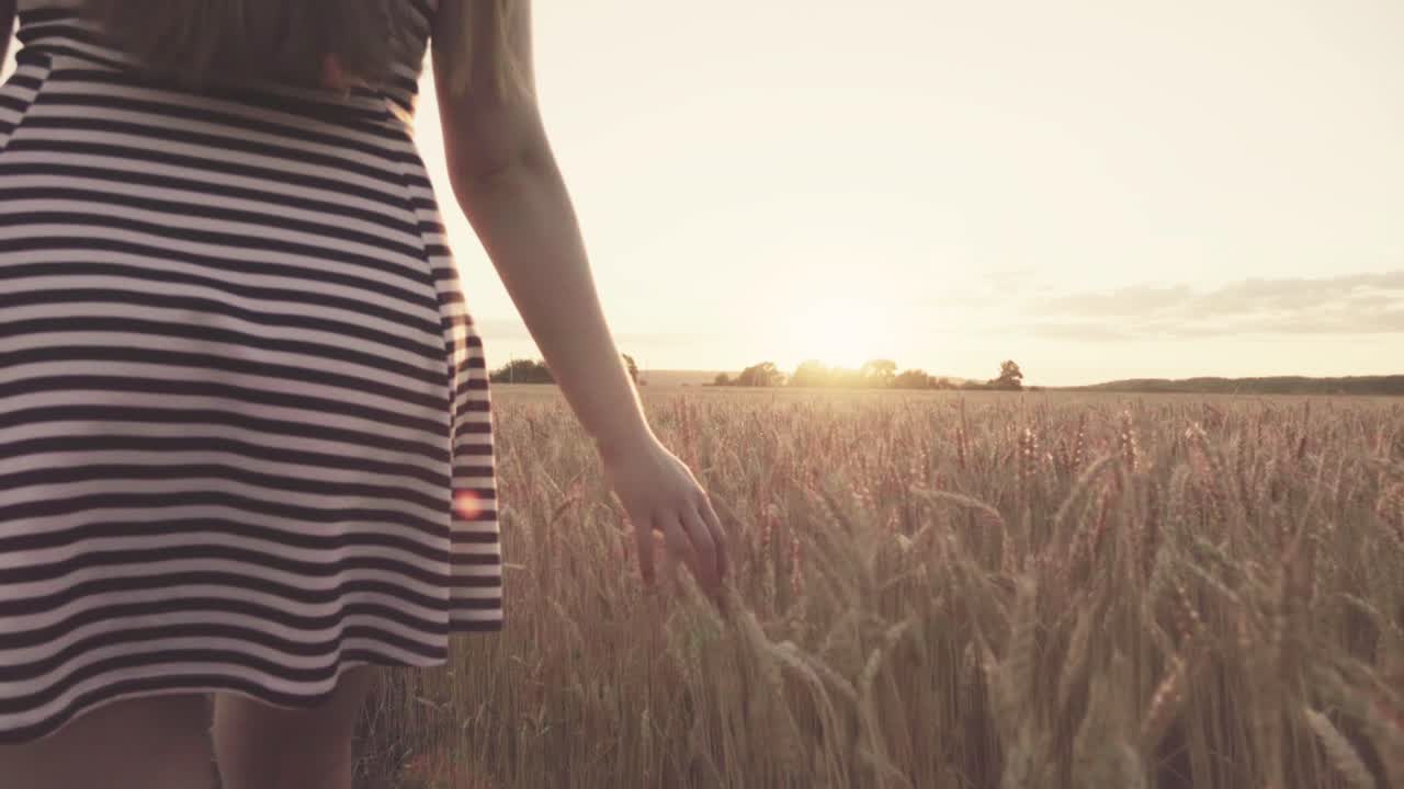 Donna che cammina in un campo di grano al tramonto