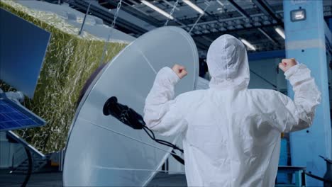 vista de atrás del científico masculino asiático celebrando el éxito mientras está de pie con la construcción de la nave espacial