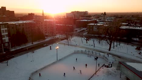 Drone-pulling-away-from-an-outdoor-rink-with-hockey-players-at-beautiful-sundown-in-Montreal,-Quebec,-Canada