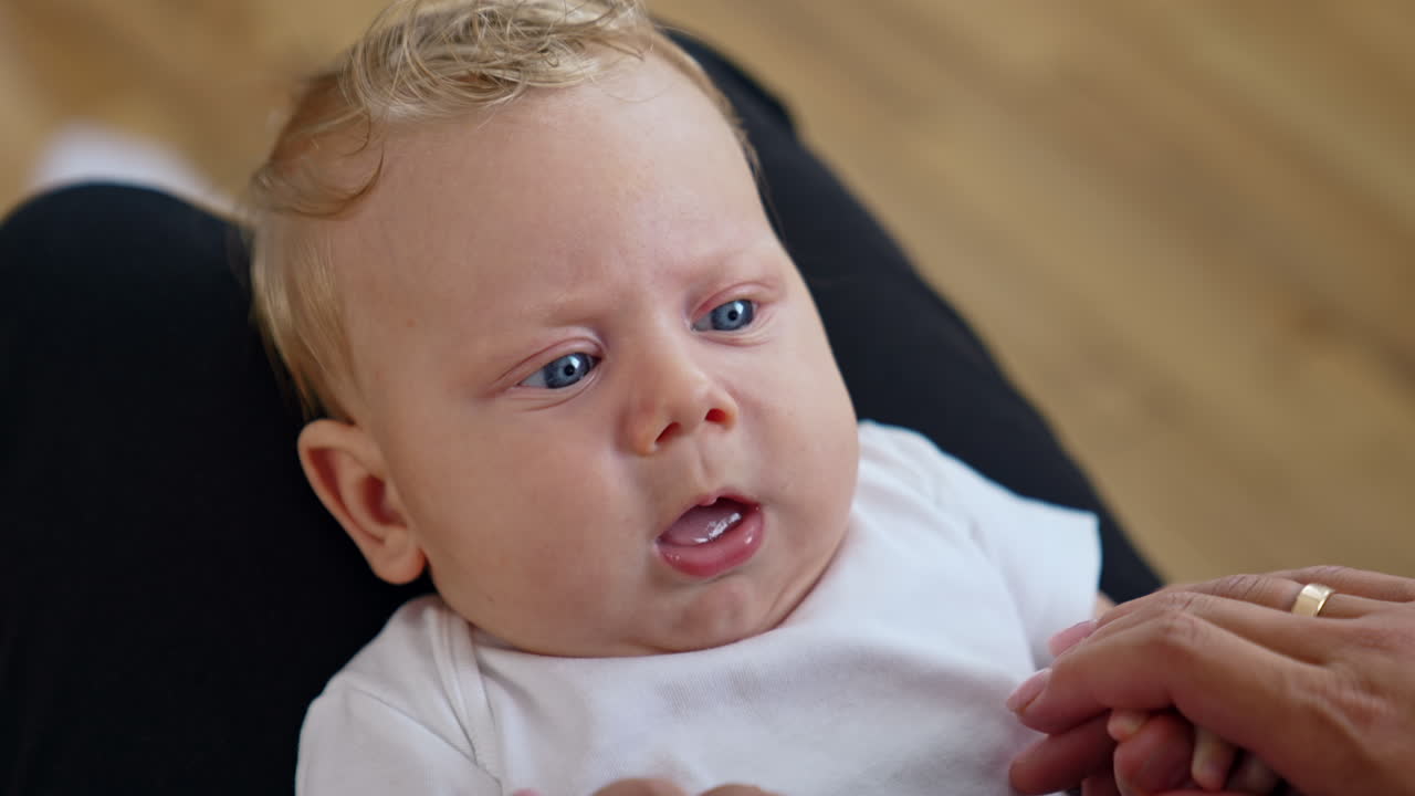 Lovely Caucasian fair-haired child with big blue eyes. Close up portrait. Baby showing tongue to parent.