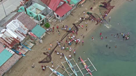 Looking-busy-view-on-the-seashore,-group-people-swimming,-walking-and-washing-fishermen-fishnet-and-drying-it-on-the-sandy-beach