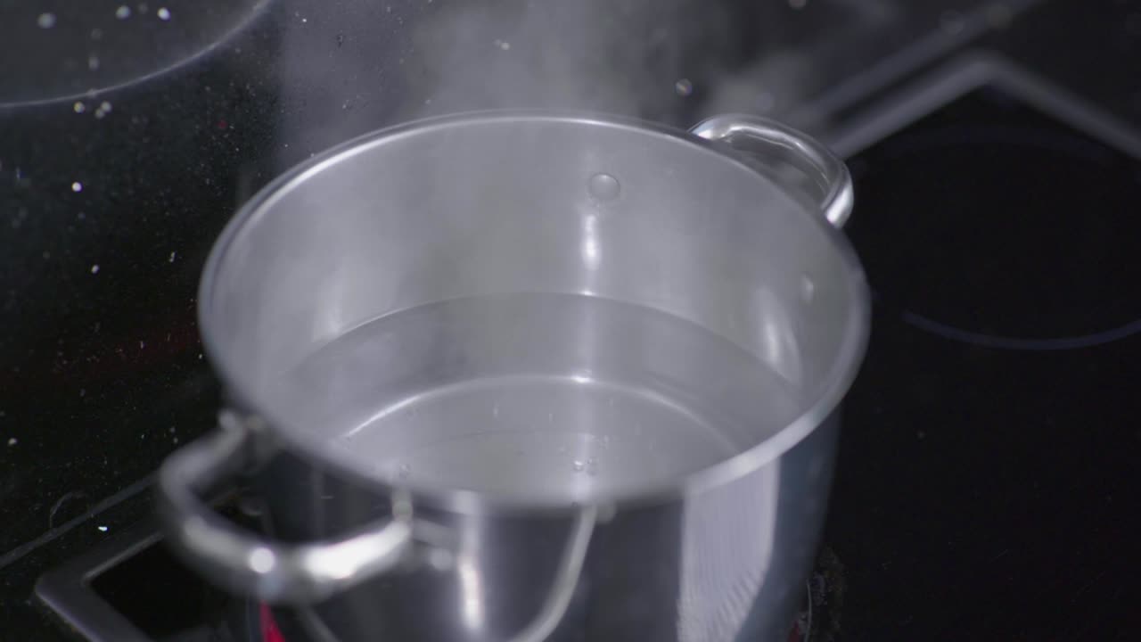 Slow motion shot of steam rising from a pot of boiling water on the stove