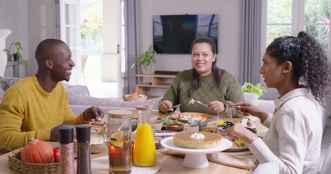 Familia afroamericana comenzando a comer en una mesa de madera, cortando comida, compartiendo cuencos, riendo